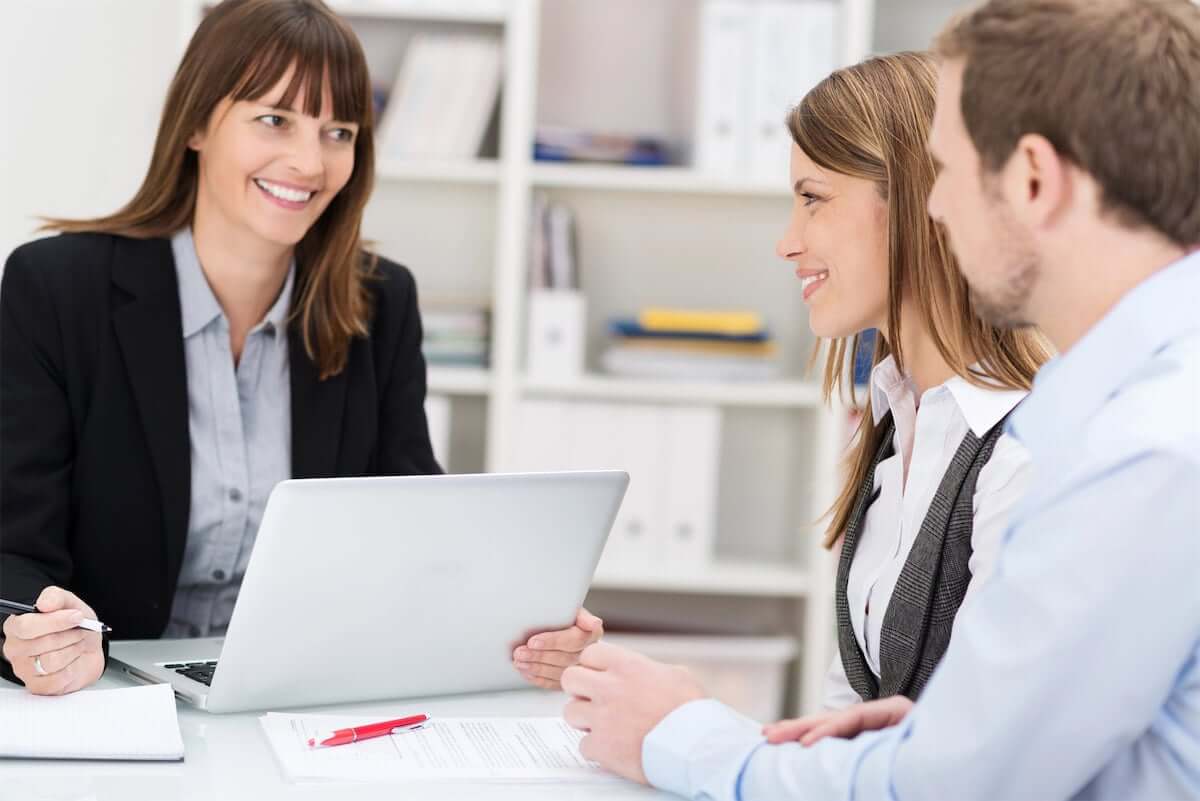Young couple talking to a woman broker
